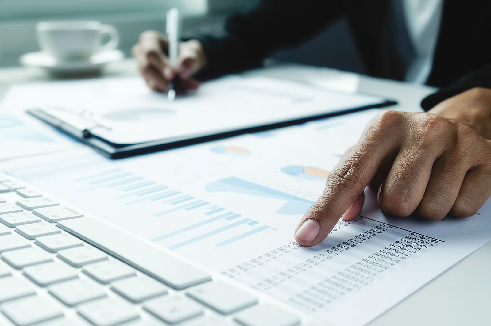 Businessperson pointing at financial charts and figures on a desk beside a laptop