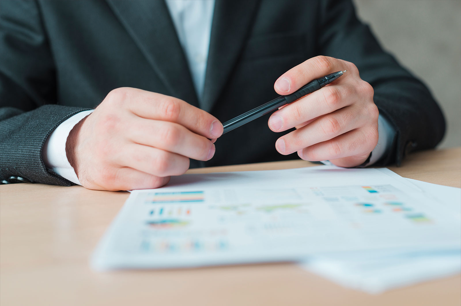 Businessman holding a pen over a colorful financial chart document